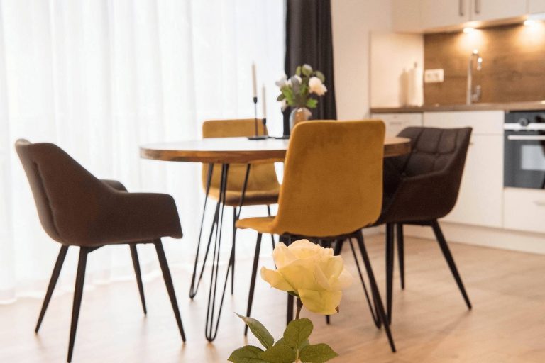 Ein Esstisch mit vier Stühlen, im Hintergrund die Küchenzeile